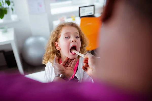 Curly appealing little girl opening mouth for pediatrician — Stock Photo, Image