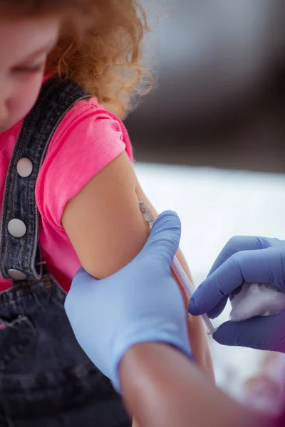 Pediatrician wearing blue gloves making injection for girl — Stock Photo, Image