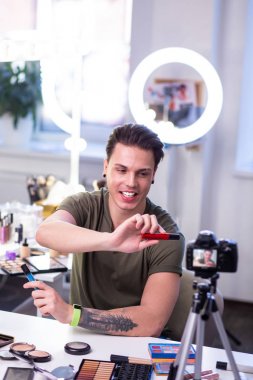 Gülümseyen yakışıklı genç adam kamera yeni ürünler sunan