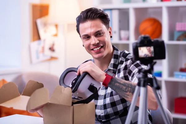 Χαμογελαστός άντρας με τατουάζ στο καρό πουκάμισο παίρνοντας VR-κράνος από χαρτόνι — Φωτογραφία Αρχείου