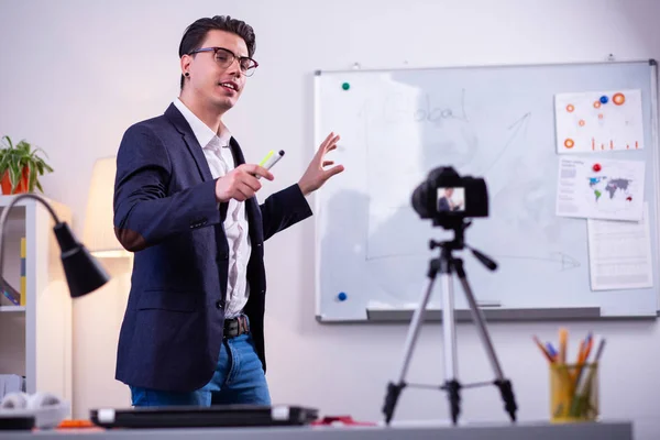 Inspired good-looking guy in clear glasses carrying markers and presenting