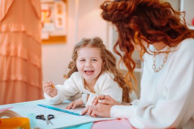 Tasarımcı olarak çalışan anne ile skeçler yapma kız gülüyor