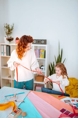 Annesi yle kırmızı kurdele kesen küçük kız