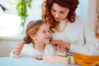 Elbise için skeçler yapan annenin yanında oturan kız