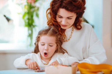 Anne elbise tasarımı yanında otururken kızı komik görünümlü