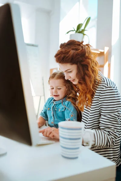 Woman working remotely spending time with her lovely daughter — Stock Photo, Image