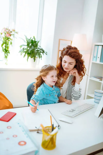 Bilgisayarda çalışan anneye katılırken neşeli kız boyama — Stok fotoğraf