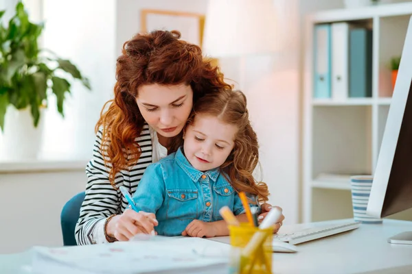 Mamá pelirroja ayudando a su niña sosteniendo la pluma y la escritura —  Fotos de Stock