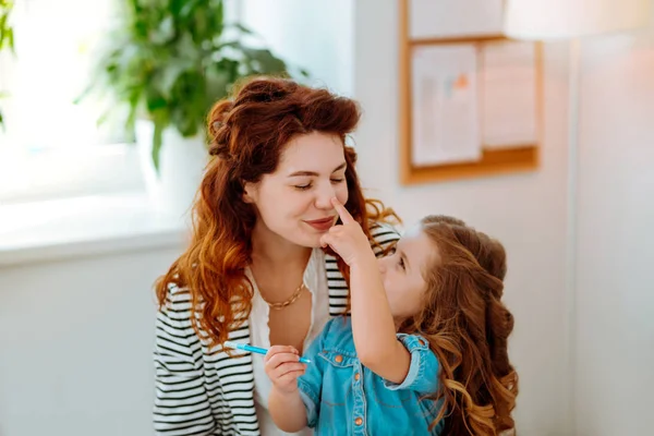 Preciosa hija tocando la nariz de su amorosa madre joven — Foto de Stock