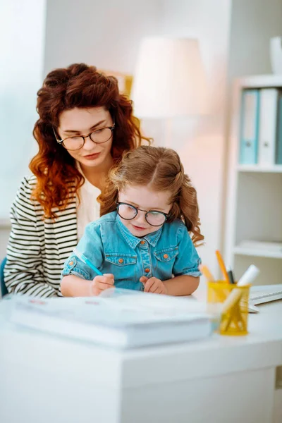 Ділова жінка дивиться її смішна дочка в окулярах живопис — стокове фото