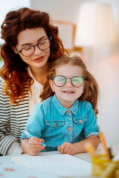 Симпатична дівчина в окулярах, що сидить біля матері, працює вдома — стокове фото
