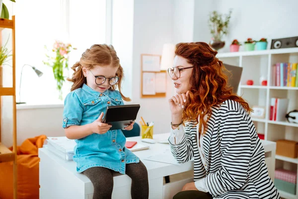 Amar a la mamá pelirroja mirando a la hija divertida usando la calculadora —  Fotos de Stock