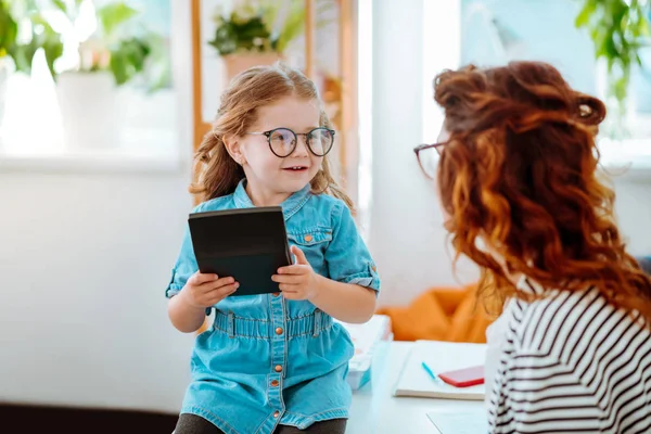 Hija sintiéndose emocionada visitando a mamá en la oficina y usando la calculadora —  Fotos de Stock