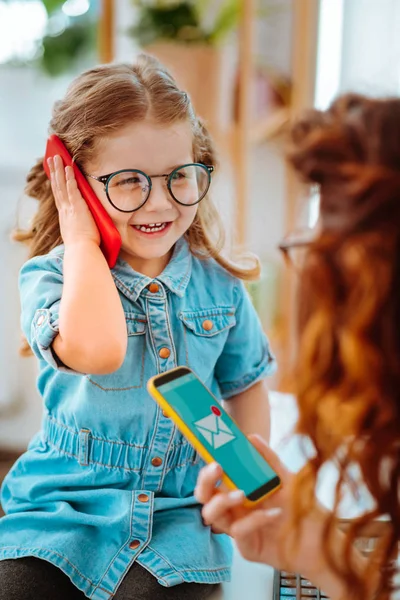 Cheerful daughter calling dad while visiting mom at work