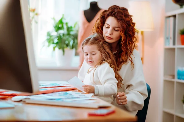 Bilgisayar çizimleri yapma üzerinde çalışan annenin dizlerinin üzerinde oturan kız