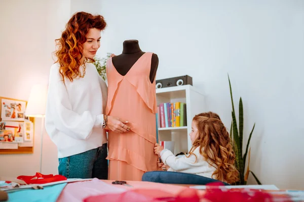 Mãe feliz sentindo memorável projetar vestido com a filha pequena — Fotografia de Stock