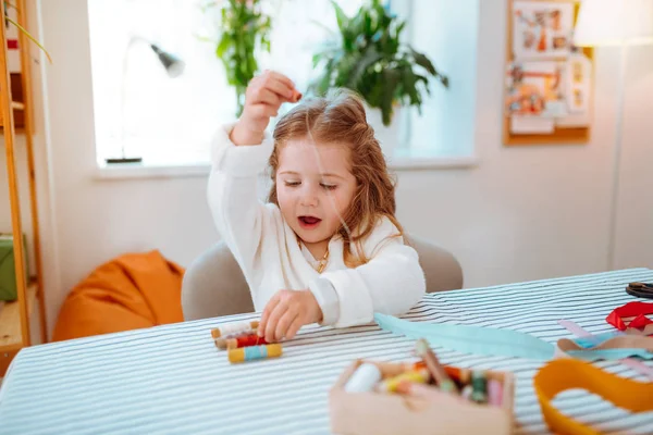 Chica sintiéndose involucrado en jugar con hilos en el taller de mamá —  Fotos de Stock
