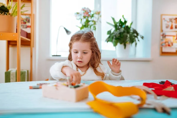 Apelando menina bonito sentado na mesa e jogando no atelier da mãe — Fotografia de Stock