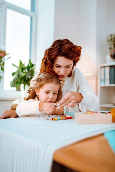 Red-haired mom showing her daughter colorful threads — Stock Photo, Image