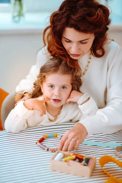 Designer entertaining daughter while playing with threads in atelier — Stock Photo, Image