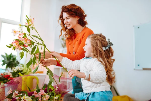 Весела дочка розважається, дивлячись на квіти з мамою — стокове фото