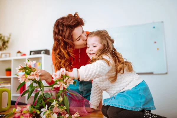 Mãe beijando sua filha depois de fazer composições florais — Fotografia de Stock