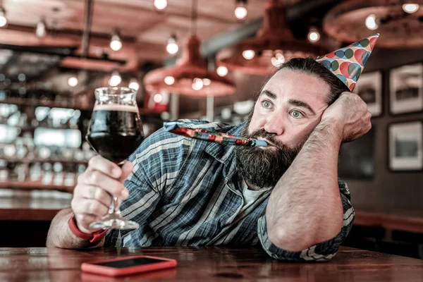 Uomo di compleanno alzando il bicchiere di birra con uno sguardo vuoto . — Foto Stock