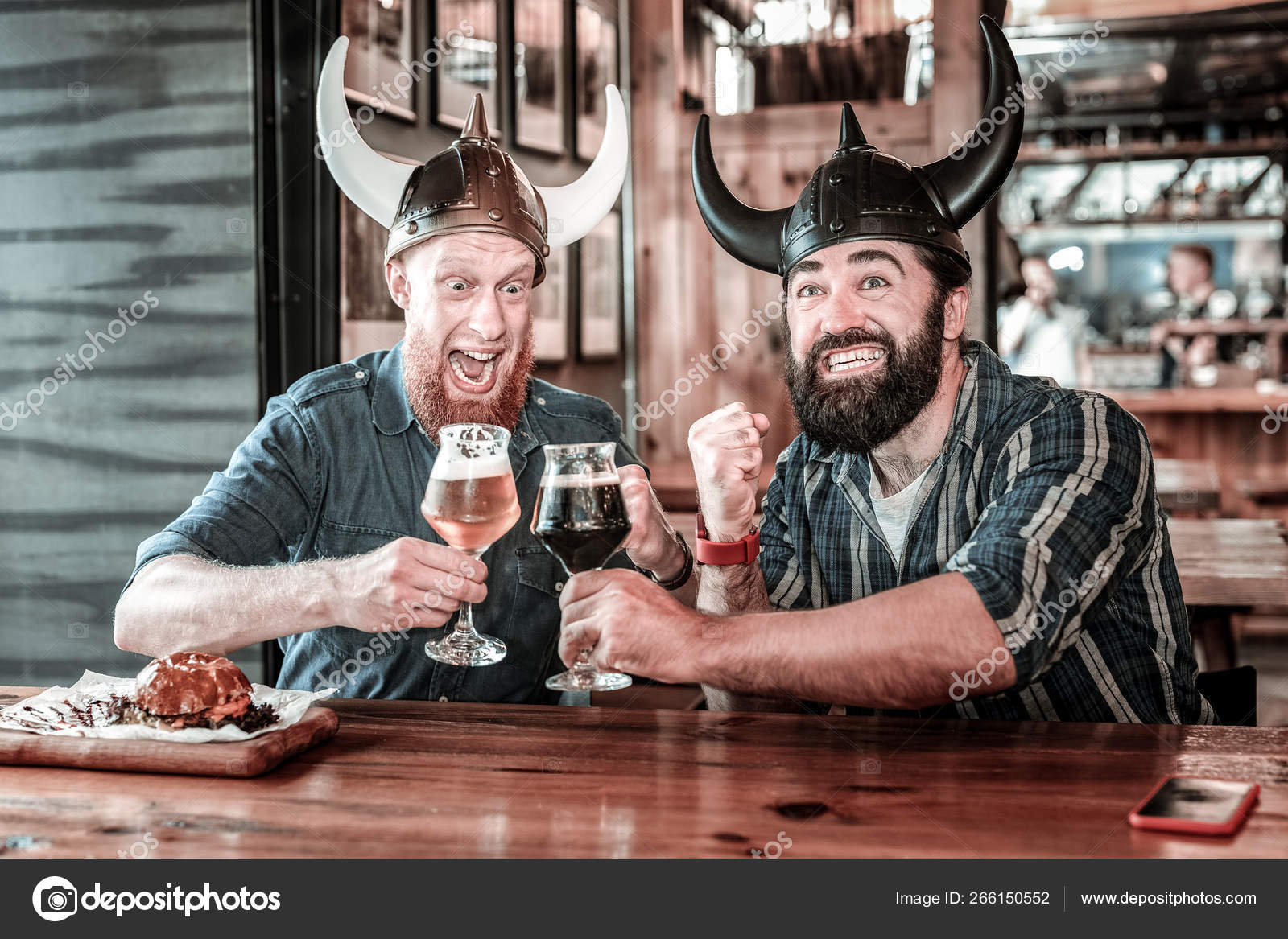 Modern smiling vikings raising glasses in a pub. Stock Photo by