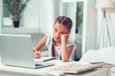 Sıkılmış yorgun küçük memnun Afro-Amerikan çocuk ders yapıyor.