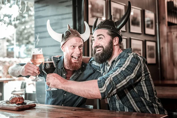 Two friends wearing viking helmets and laughing.