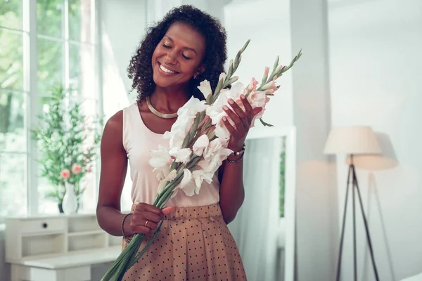 Bella donna afro-americana che gode di un bellissimo bouquet di gladioli . — Foto Stock