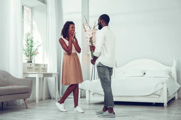 Shocked woman getting flowers from her handsome appealing husband — Stock Photo, Image
