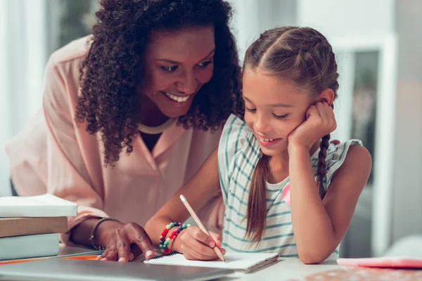 Charmig afro-amerikansk mamma hjälpa hennes söta schoolkid med en läxa. — Stockfoto