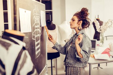 Moda tasarımcısı yeni bir elbisenin detaylarını düşünüyor.