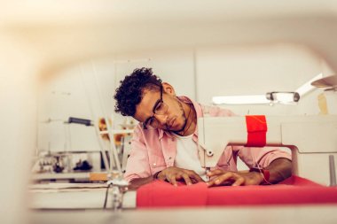 Young man sewing a dress in a studio. clipart