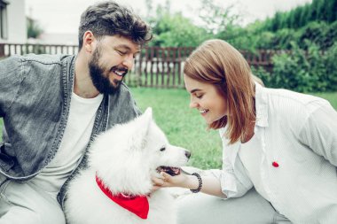 Yüz portre genç-yetişkin bayan şefkatle büyük bir beyaz köpek petting.