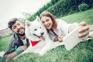 Neşeli çift bir köpek ile eğlenmek ve selfie çekmek.