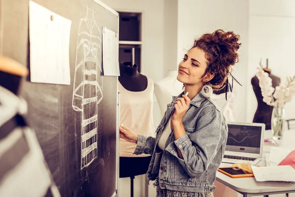 Diseñadora de ropa mirando felizmente sus bocetos . — Foto de Stock