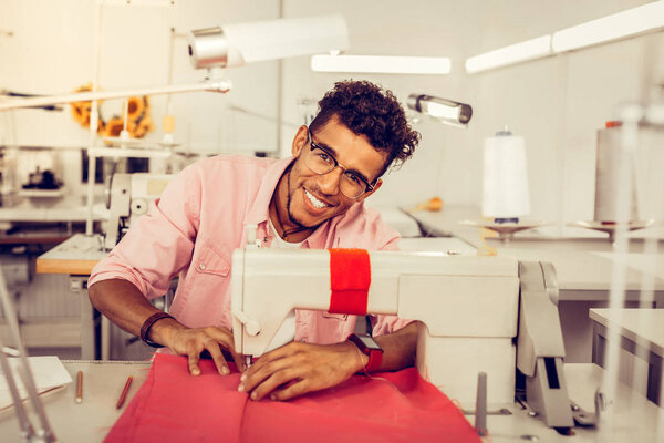 Красивый дизайнер сшивает платье швейной машинкой
.