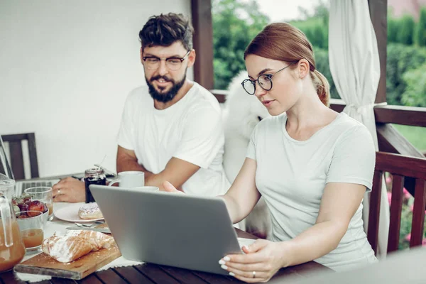 Gericht vrouwelijk werken op laptop tijdens het ontbijt met man buitenshuis. — Stockfoto
