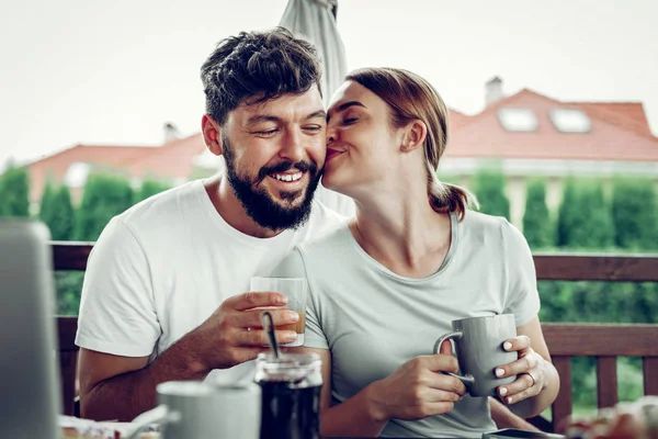 Okouzlující manželka líbá manžela při snídani venku. — Stock fotografie