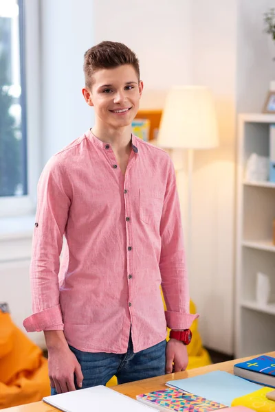 Adolescente con jeans y camisa rosa de pie cerca de la mesa —  Fotos de Stock