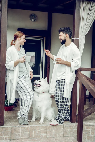 Couple contesté dégustant le café du matin tout samoyed assis à côté . Images De Stock Libres De Droits