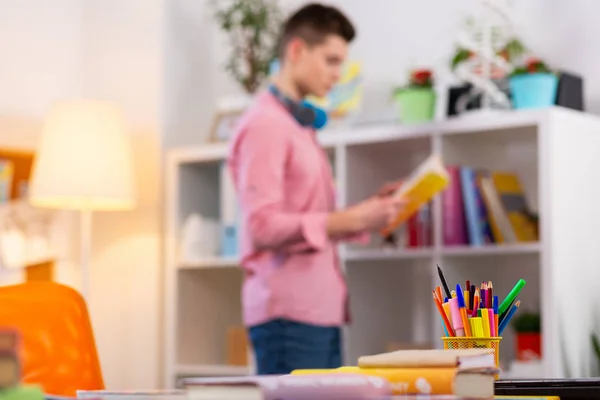 Tavolo con cancelleria e libri vicino libro di lettura per studenti — Foto Stock