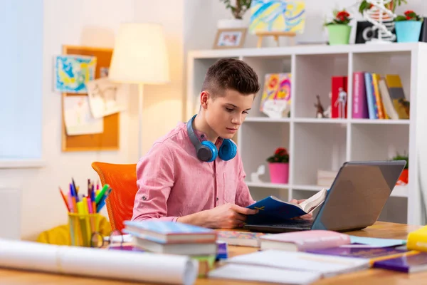 Підліток сидить за столом навчається за допомогою ноутбука та книг — стокове фото