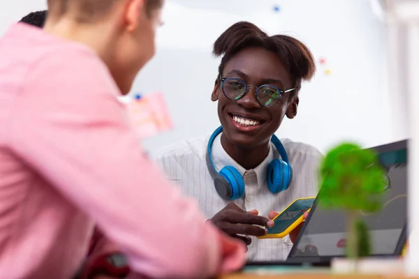 Estudiante de piel oscura con gafas sentado cerca de sus amigos — Foto de Stock