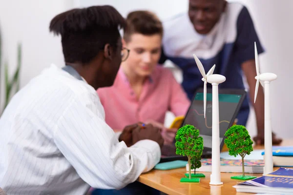 Modellen van windmolens staande op tafel in de buurt van drie slimme studenten — Stockfoto