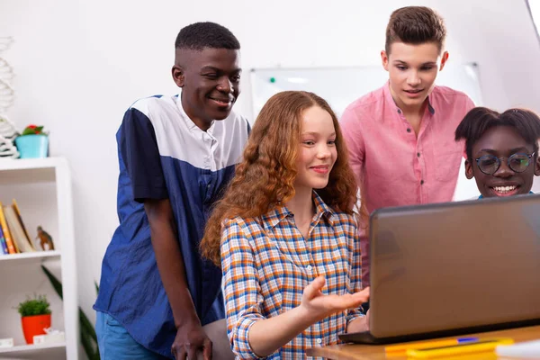 Girl watching online lesson with boys while studying together