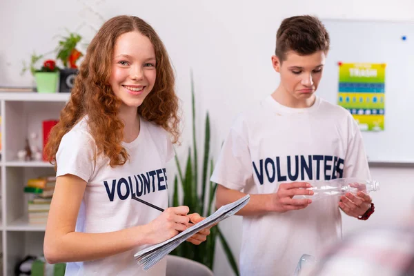 Meisje glimlachend tijdens het sorteren van afval met haar beste vriend op school — Stockfoto