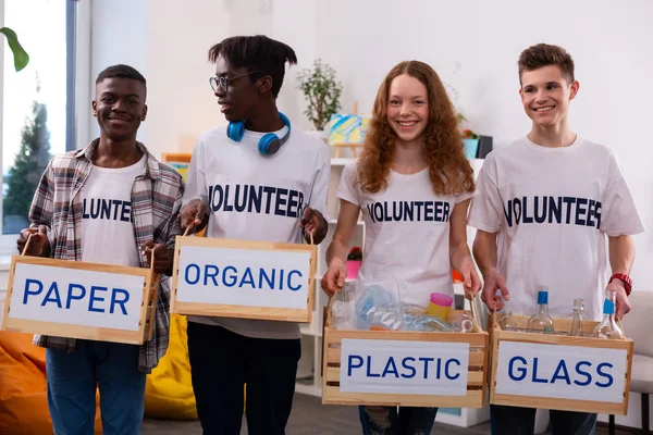 Adolescentes sosteniendo cajas con diferentes tipos de basura después de la clasificación — Foto de Stock